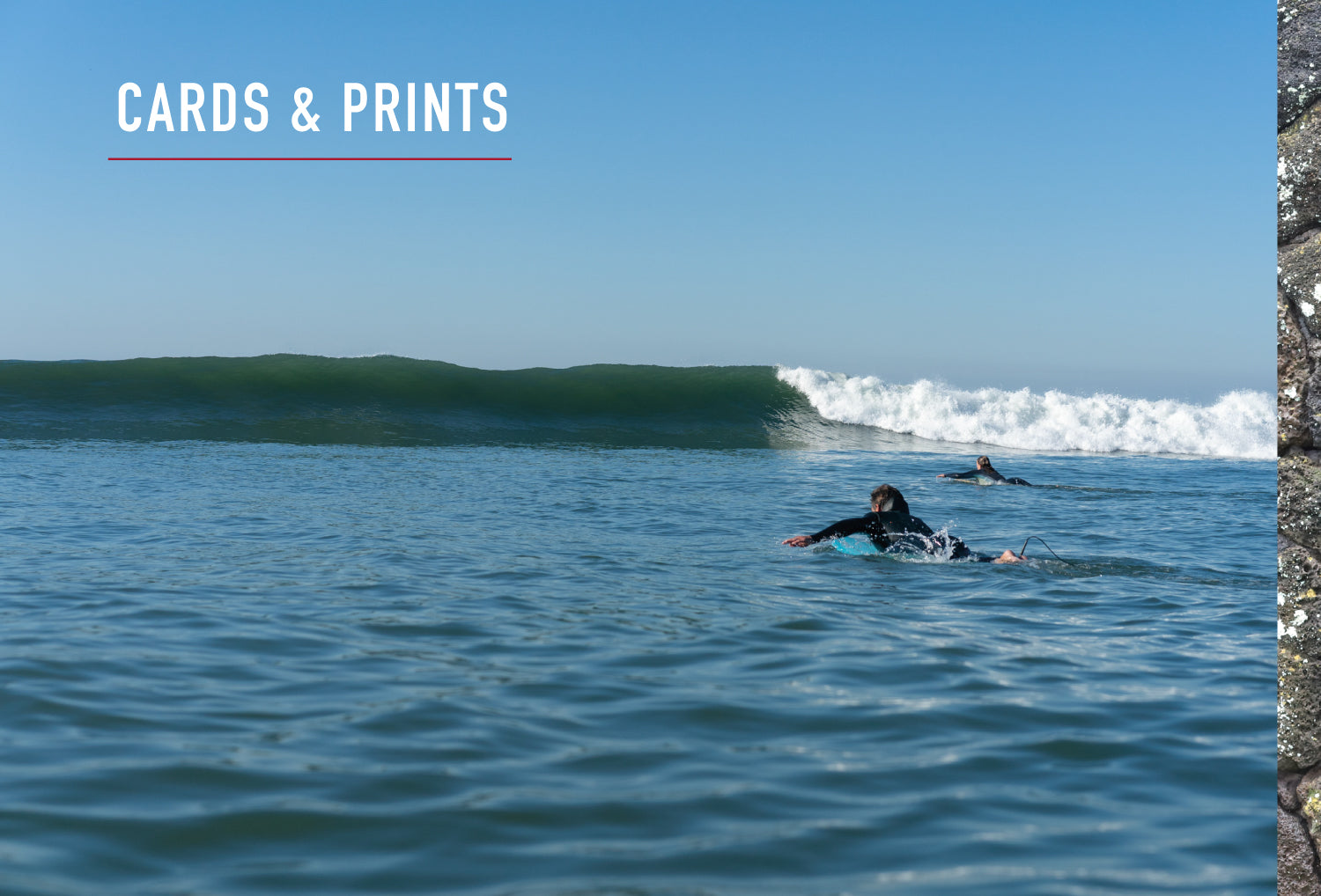 Cards & prints header. Two surfers paddling out with wave coming in.