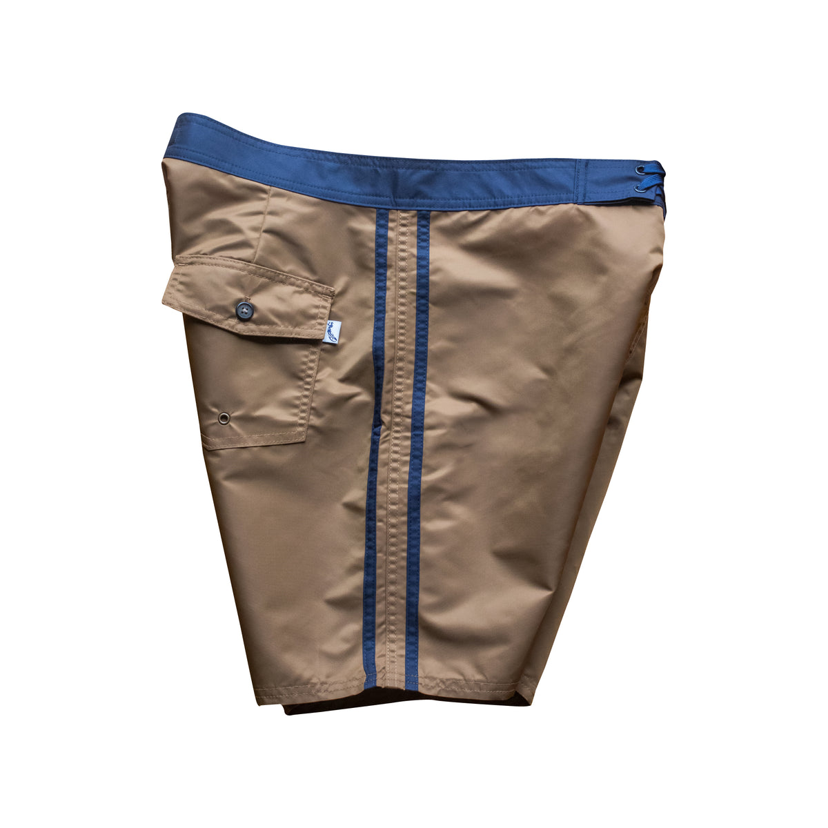 Side view of vintage style surf trunks in coyote brown with navy trim and navy stripes on side. Material is a durable satin nylon. Severson icon label on back pocket.