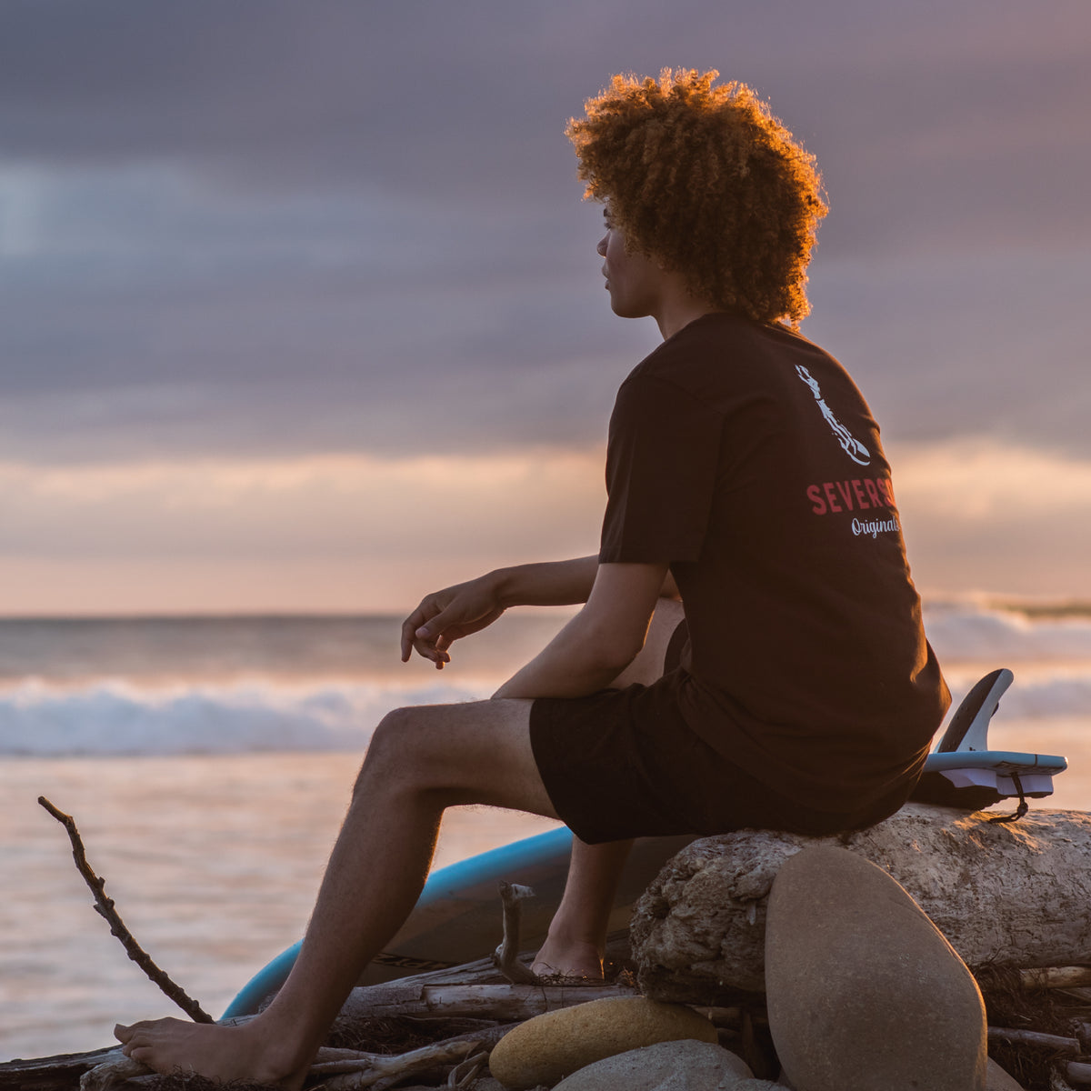 Surfer checking to the waves at Lower Trestles during sunset, wearing the Soul Arch tee in black.