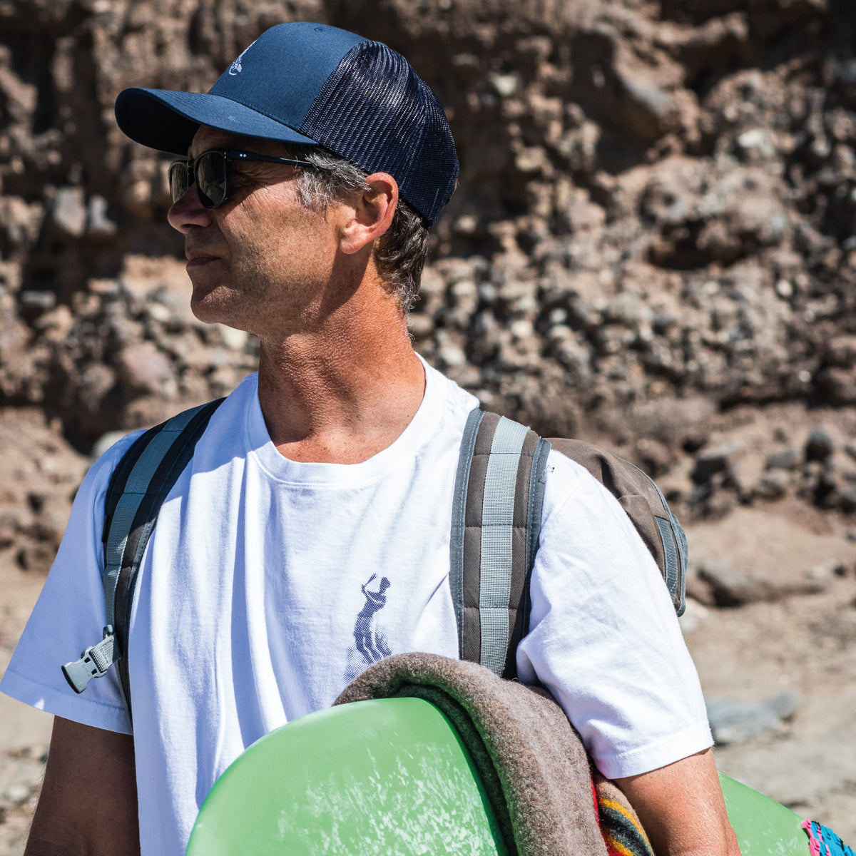 Photo of surfer wearing the icon hat walking on beach with surfboard at Dana Point, California.